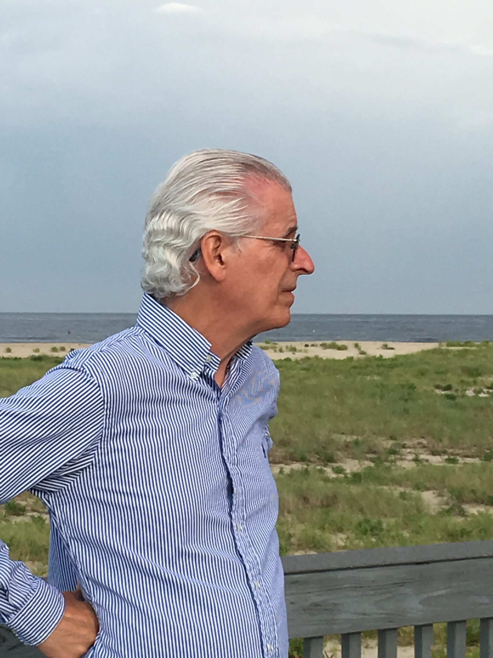 Elderly man with white hair looking at the horizon outdoors.